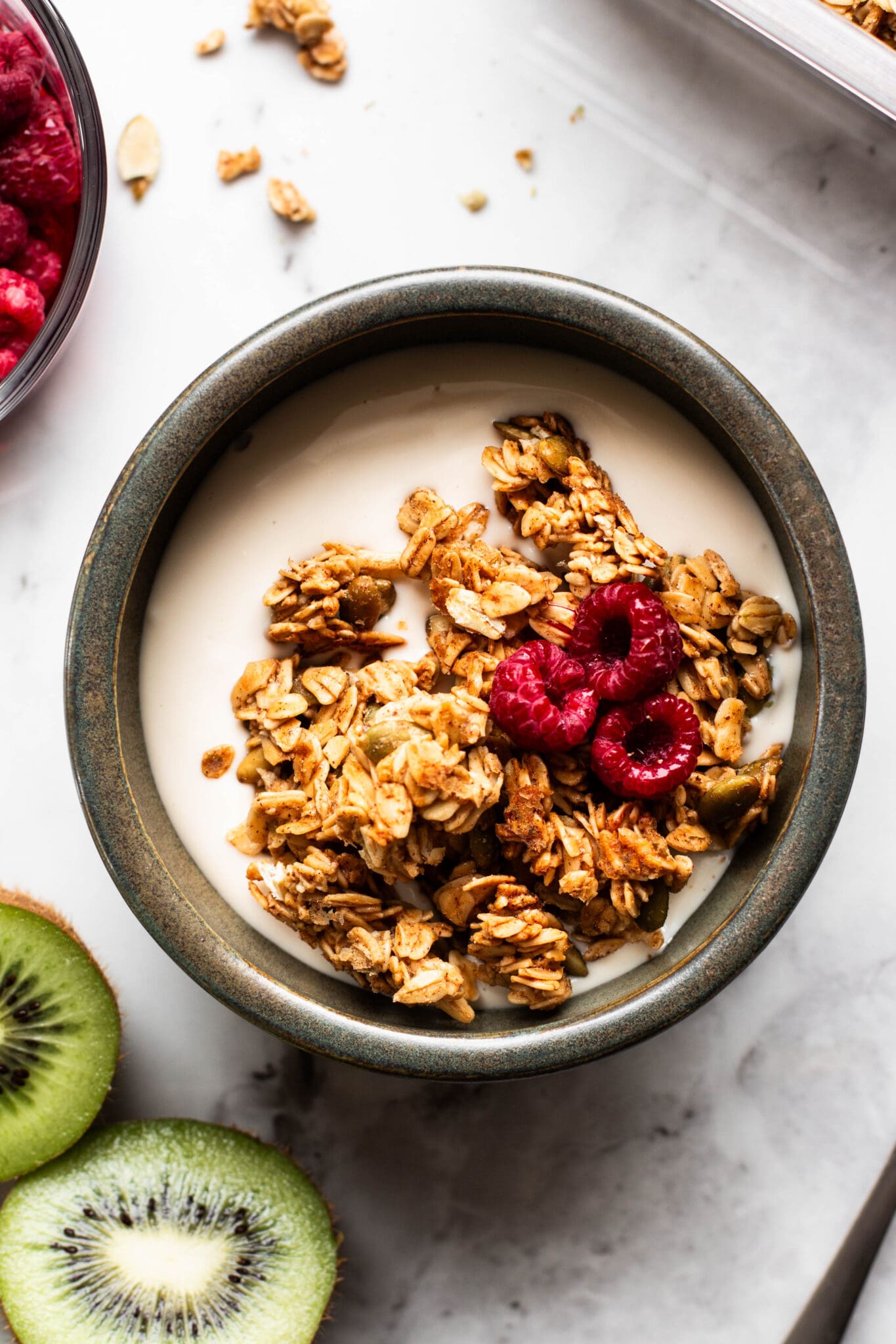 Weekly meal prep granola in a bowl with yogurt and raspberries, seen from the top